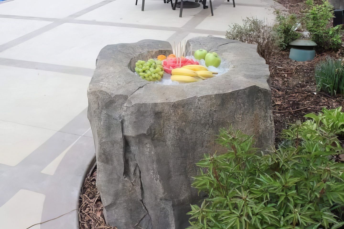 Fruit arranged on a stone pedestal in a garden walkway