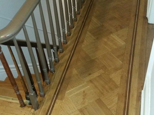 A wooden staircase with a metal railing and a wooden floor