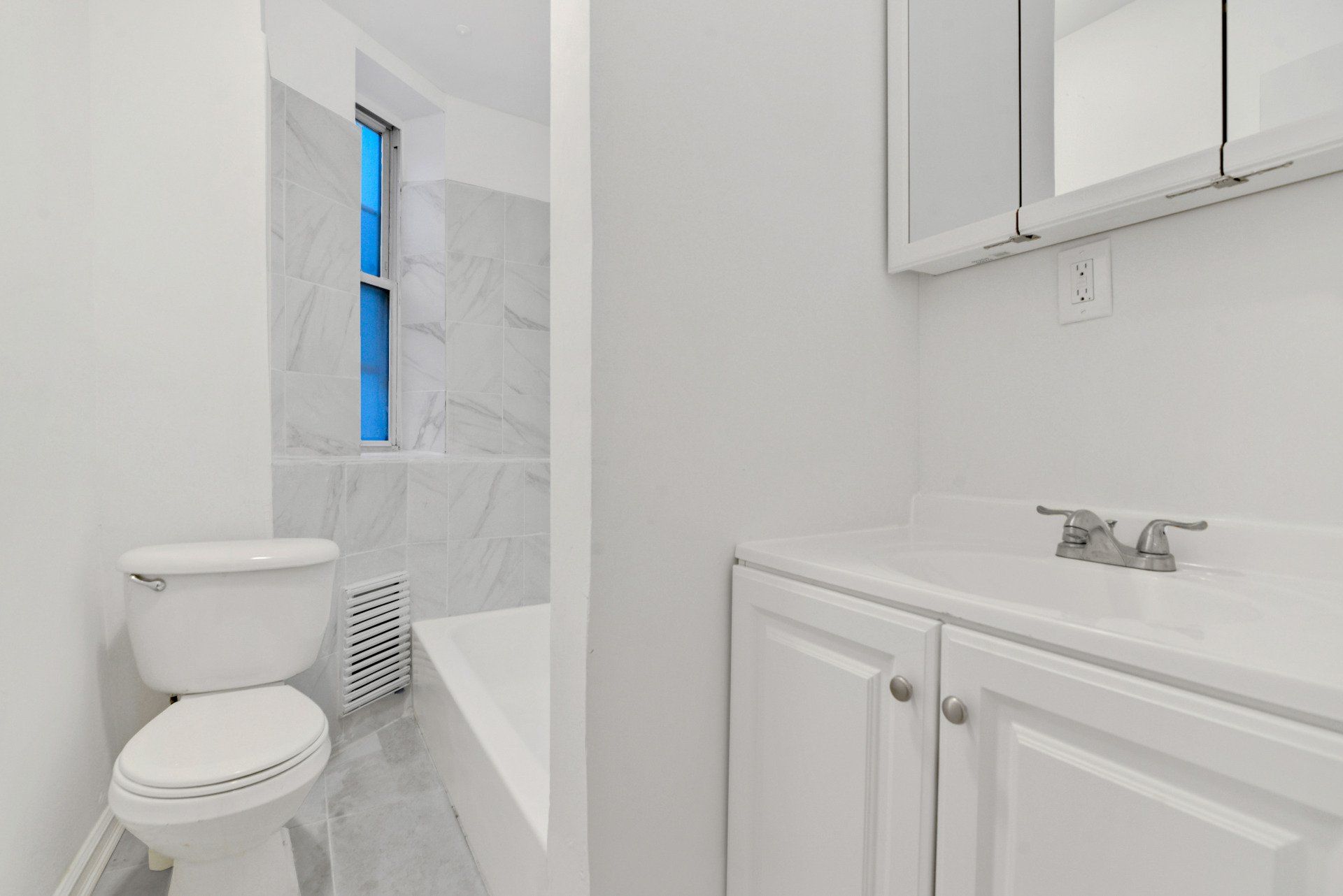 A bathroom with a toilet , sink , and mirror.