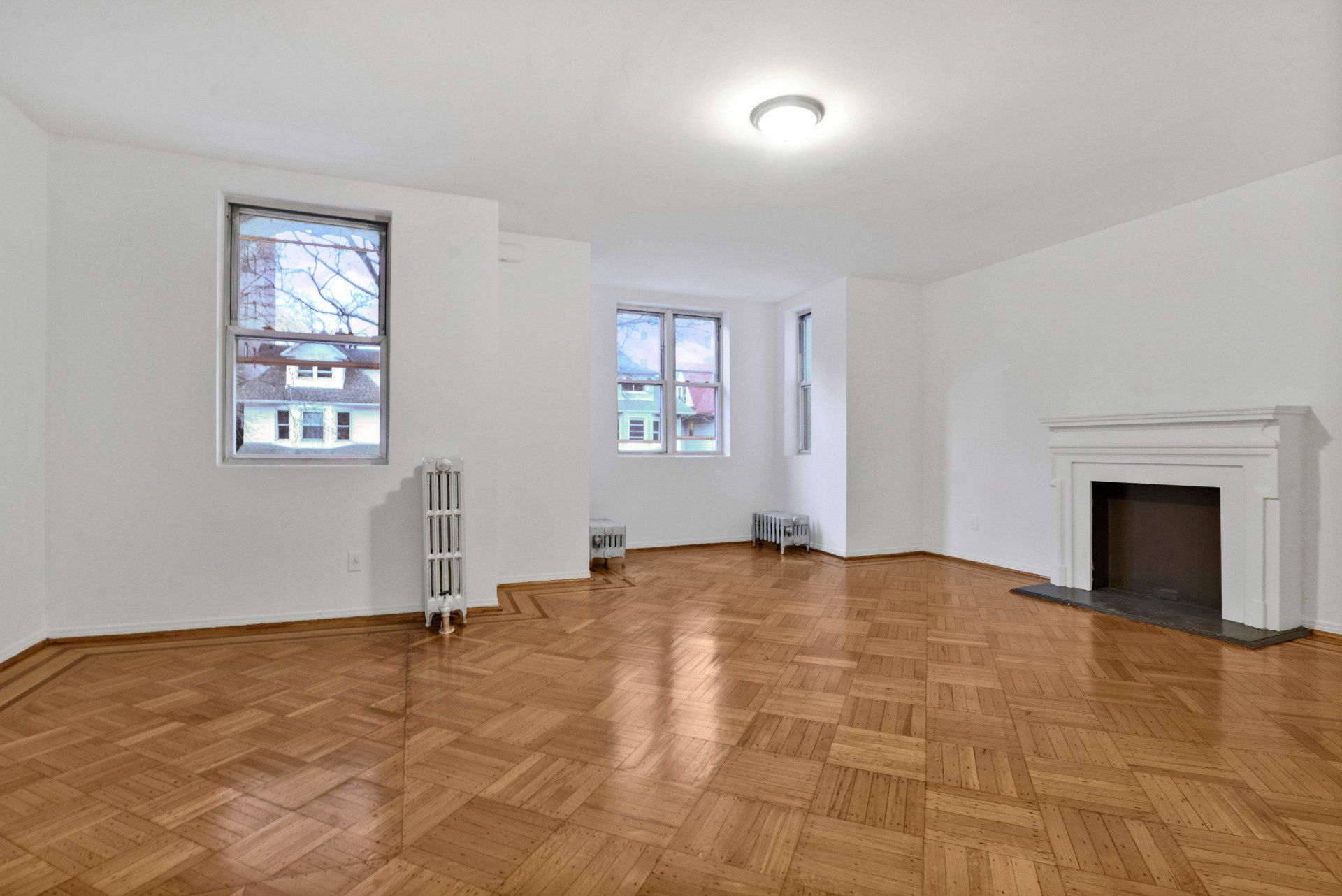 An empty living room with hardwood floors and a fireplace