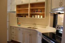 A kitchen with white cabinets , a sink , a stove , and a refrigerator.