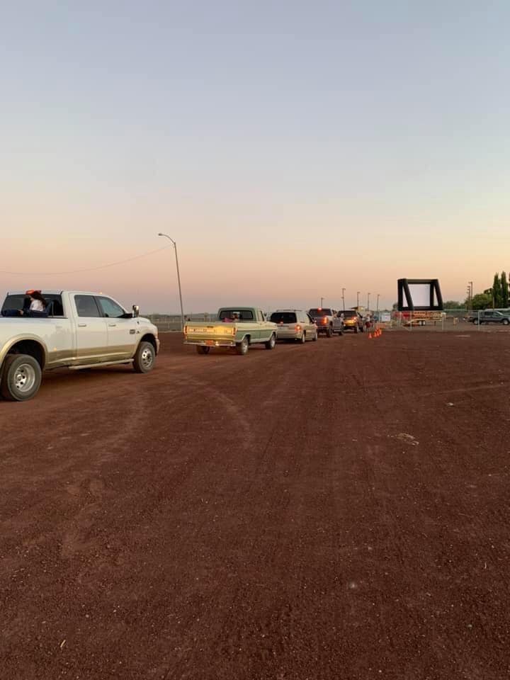 A row of trucks are parked in a dirt lot.