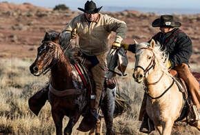 Two men are riding horses in a field.