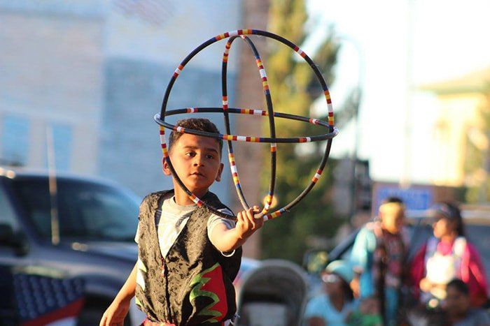 A young boy is holding a hula hoop in his hand