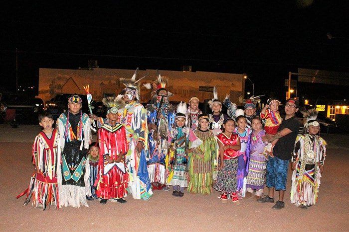 A group of people in native american costumes are posing for a picture.
