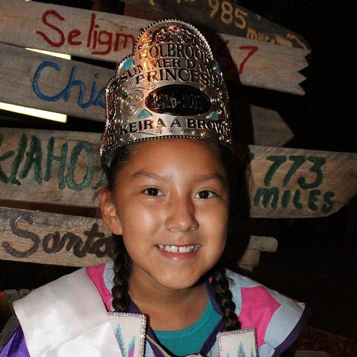 A little girl wearing a crown that says ' princess ' on it