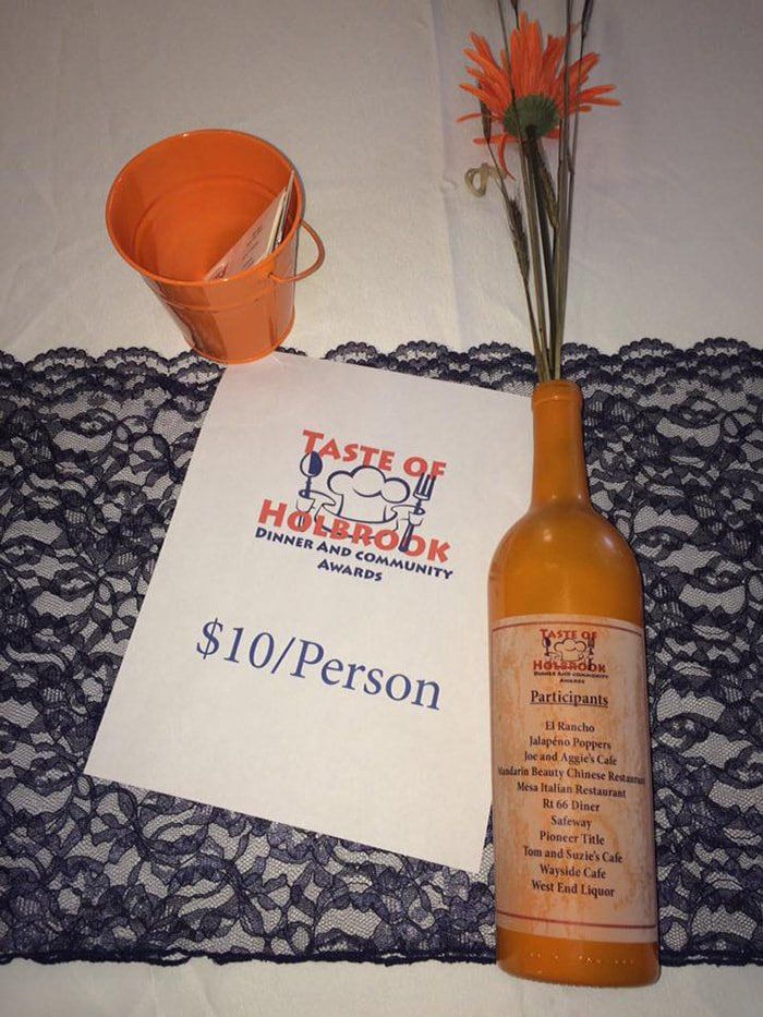 A bottle of orange juice sits on a table next to a paper that says $ 10 / person