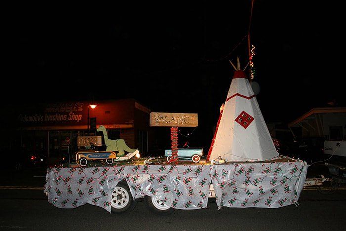 A float in a parade with a teepee and a jeep on it.