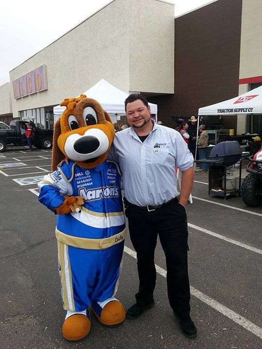 A man standing next to a mascot wearing a racing suit