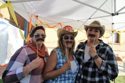 Three women wearing cowboy hats and fake mustaches are posing for a picture.
