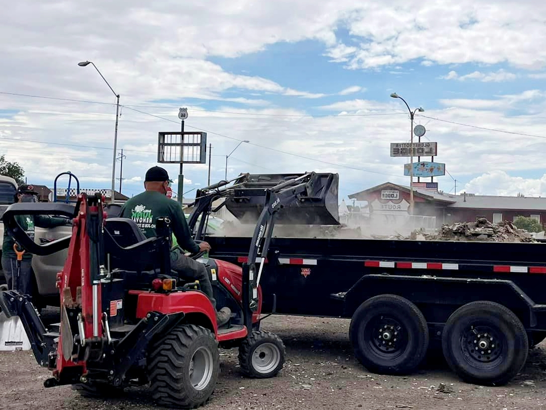 A man is driving a tractor next to a dump truck.