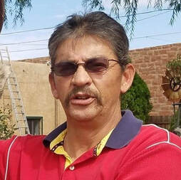 A man with a mustache is wearing sunglasses and a red shirt.