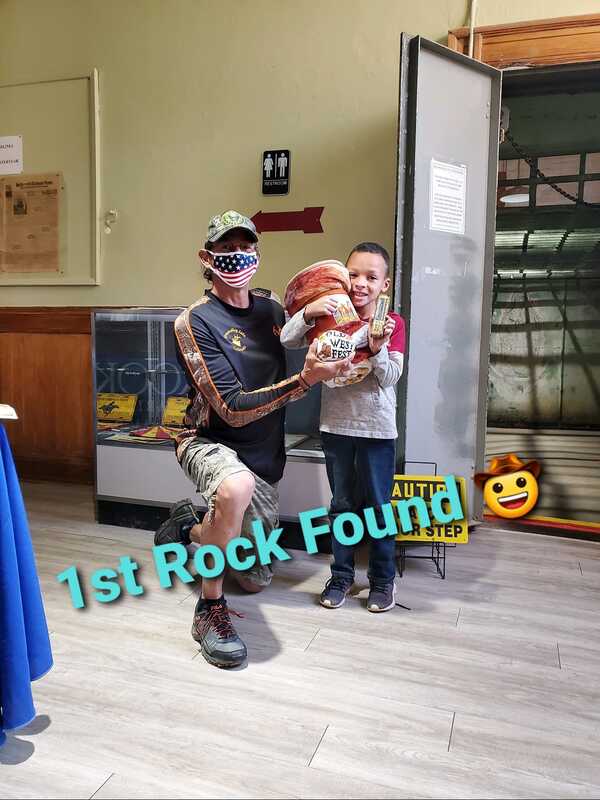 A man holding a snake next to a boy with the words 1st rock found written on the floor