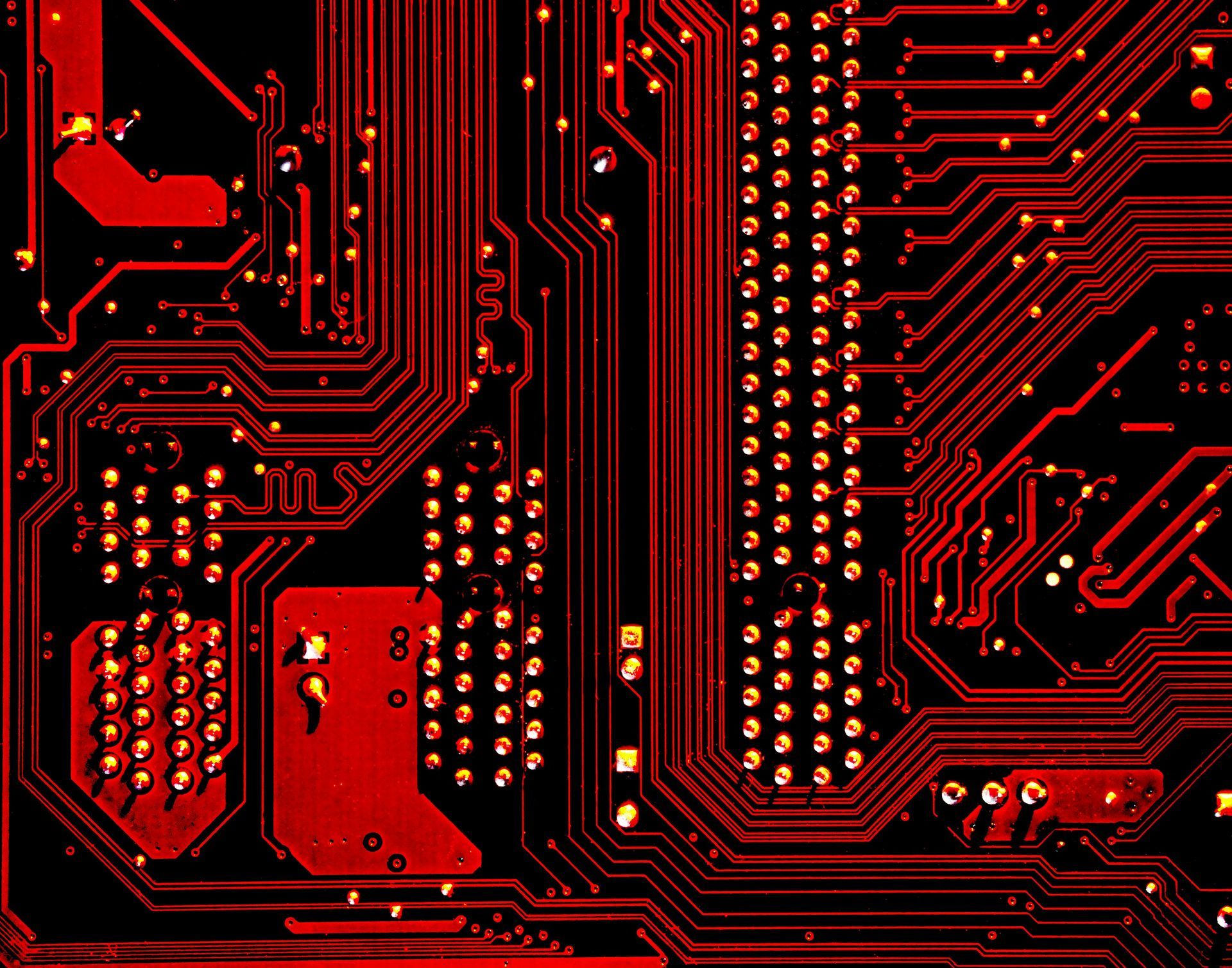 A close up of a red circuit board on a black background.