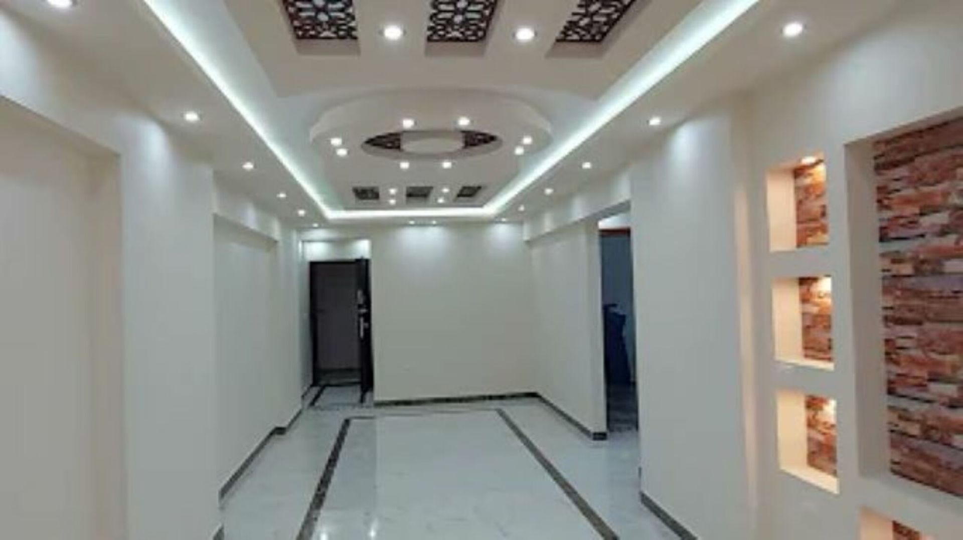 A long hallway with a brick wall and a ceiling light.