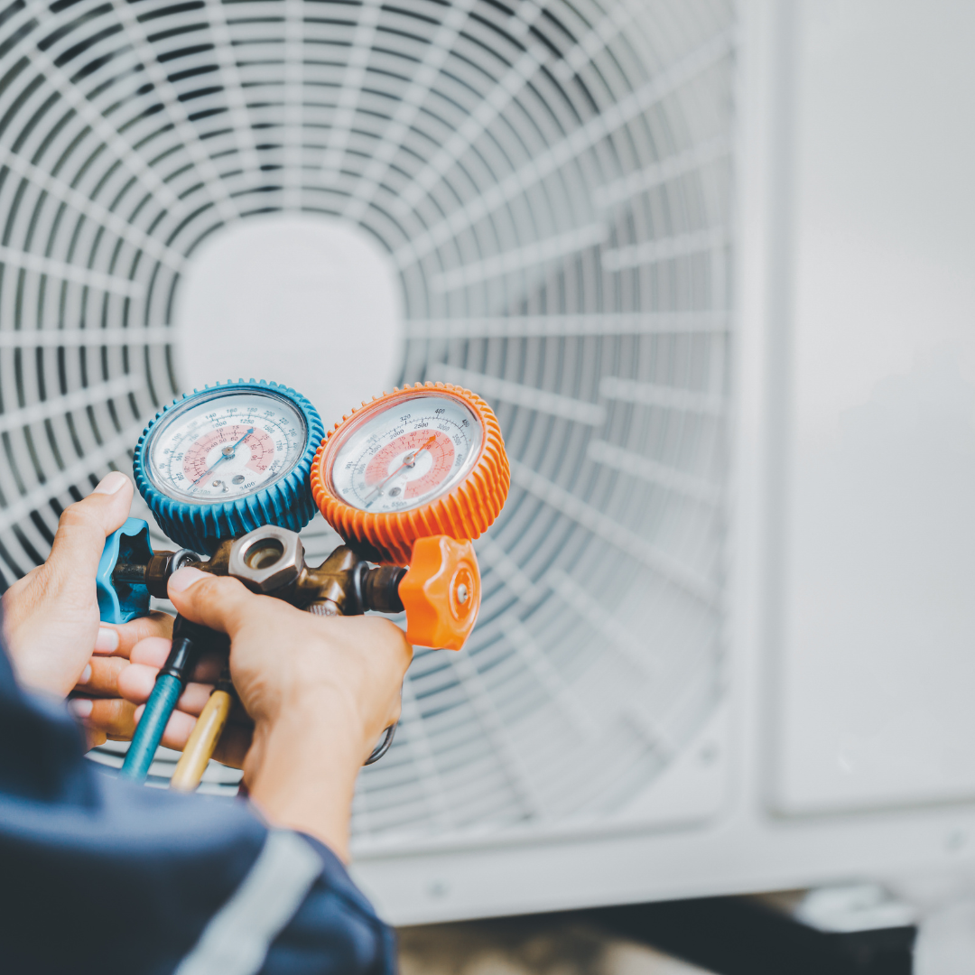 A person is holding two gauges in front of a fan.