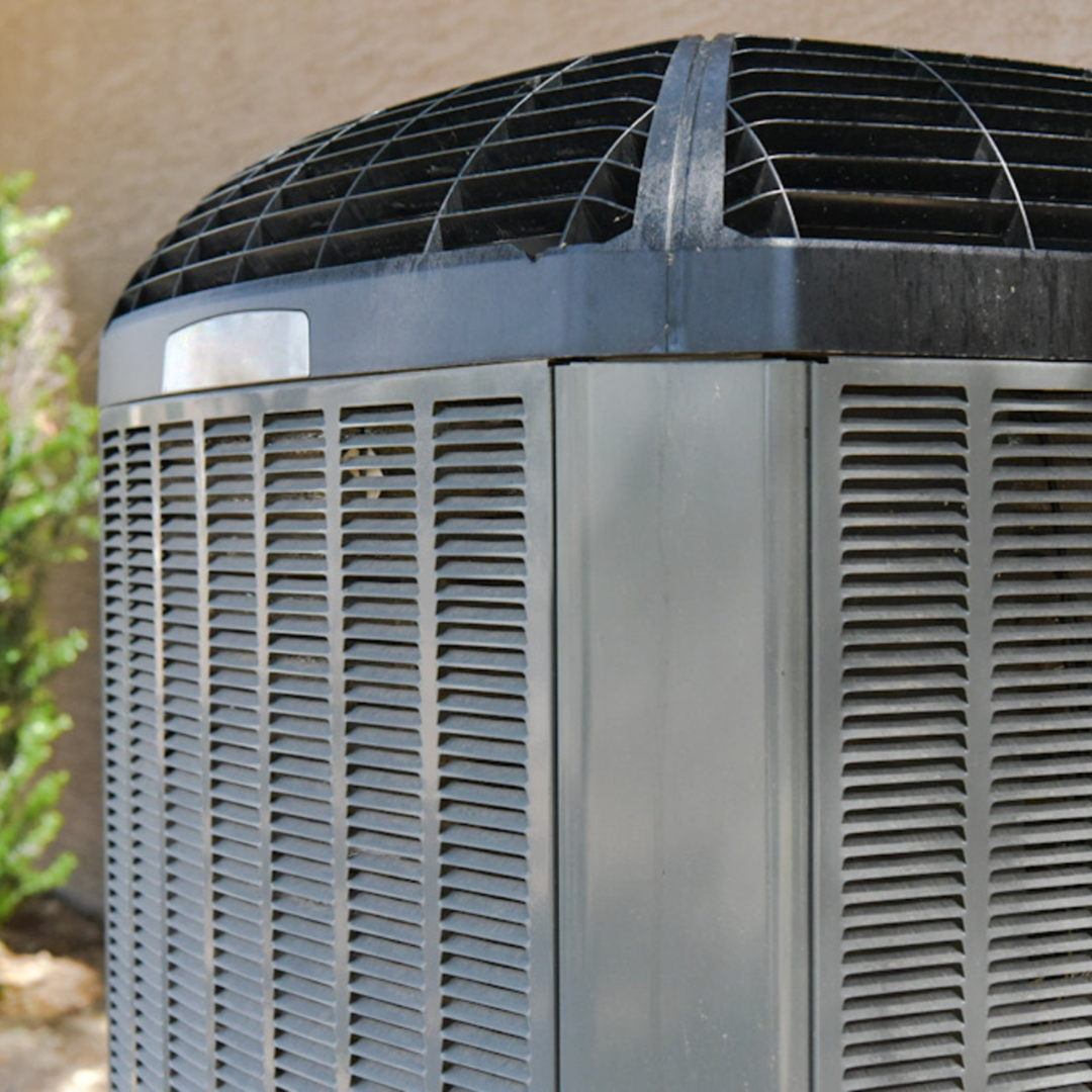 A large gray air conditioner is sitting outside of a building.
