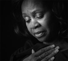 Woman with hand over chest, eyes closed, possibly in grief.