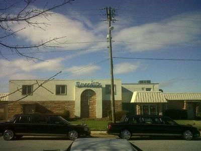 Two black limousines parked in front of a building with the word 