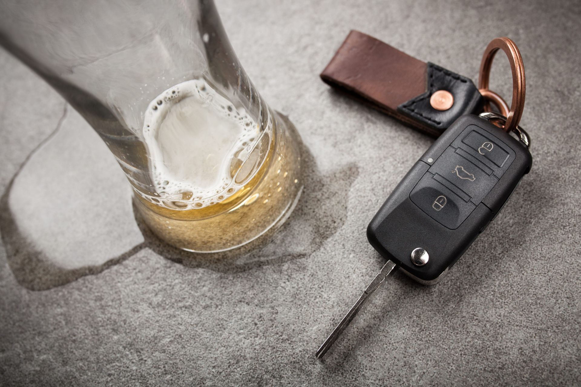 Beer glass and car key fob on a gray surface