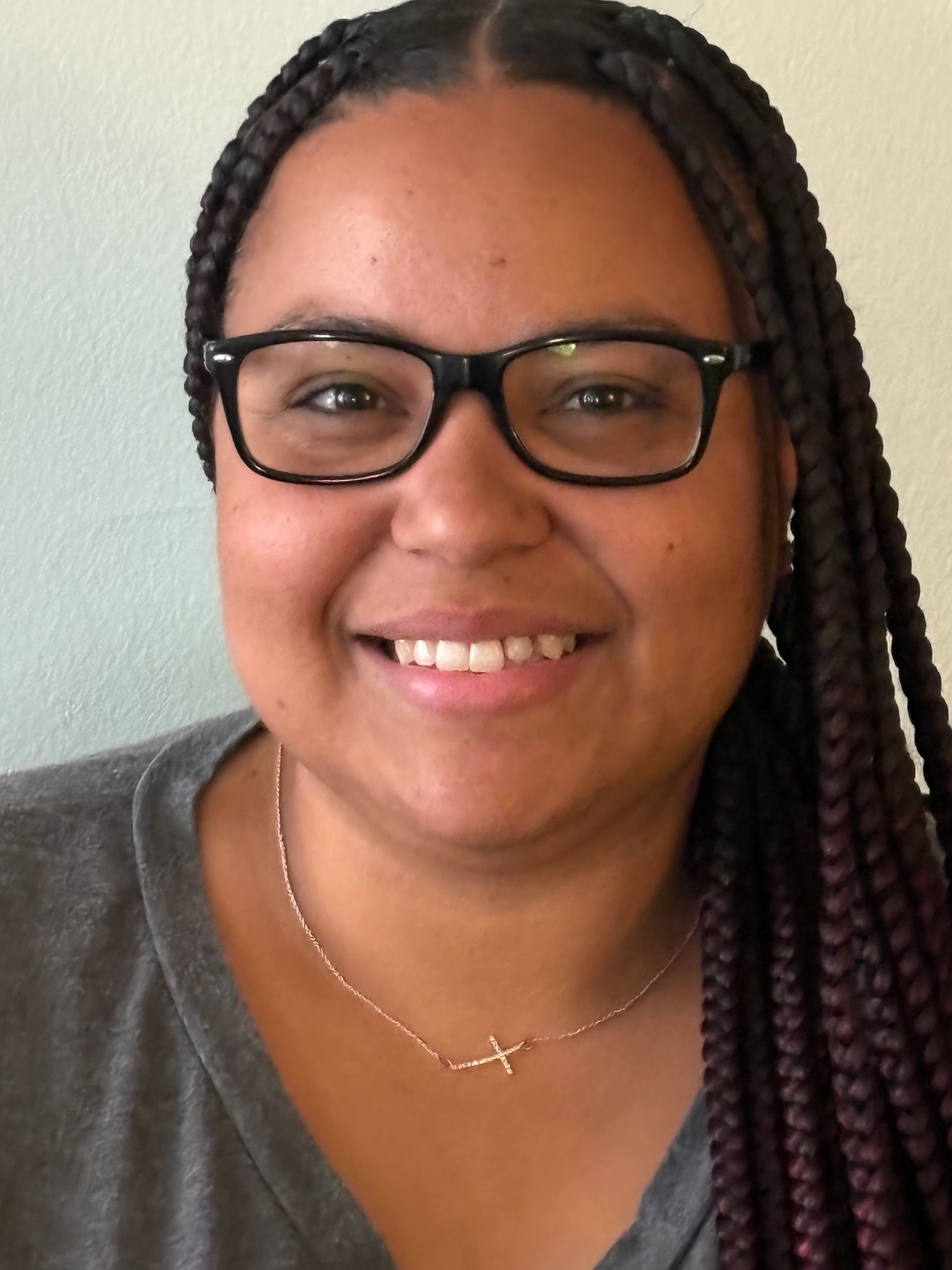 Woman with glasses and braids smiling.