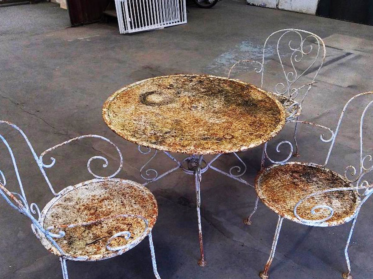 Une table et des chaises rouillées posées sur une surface en béton