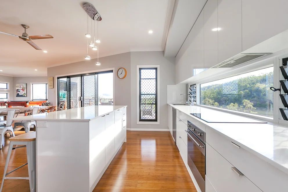 Modern All White Kitchen With Lights Hanging From The Ceiling — Engineering And Drafting Services In Yeppoon, QLD