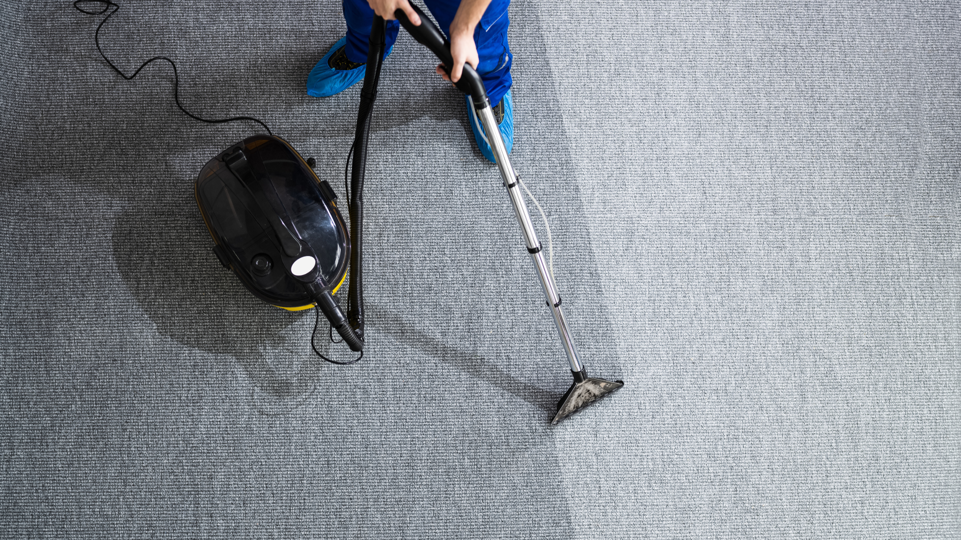 A person is using a vacuum cleaner to clean a carpet.