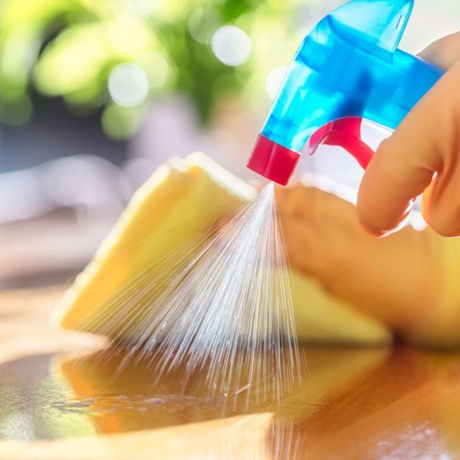 A person is spraying a sponge with a spray bottle.