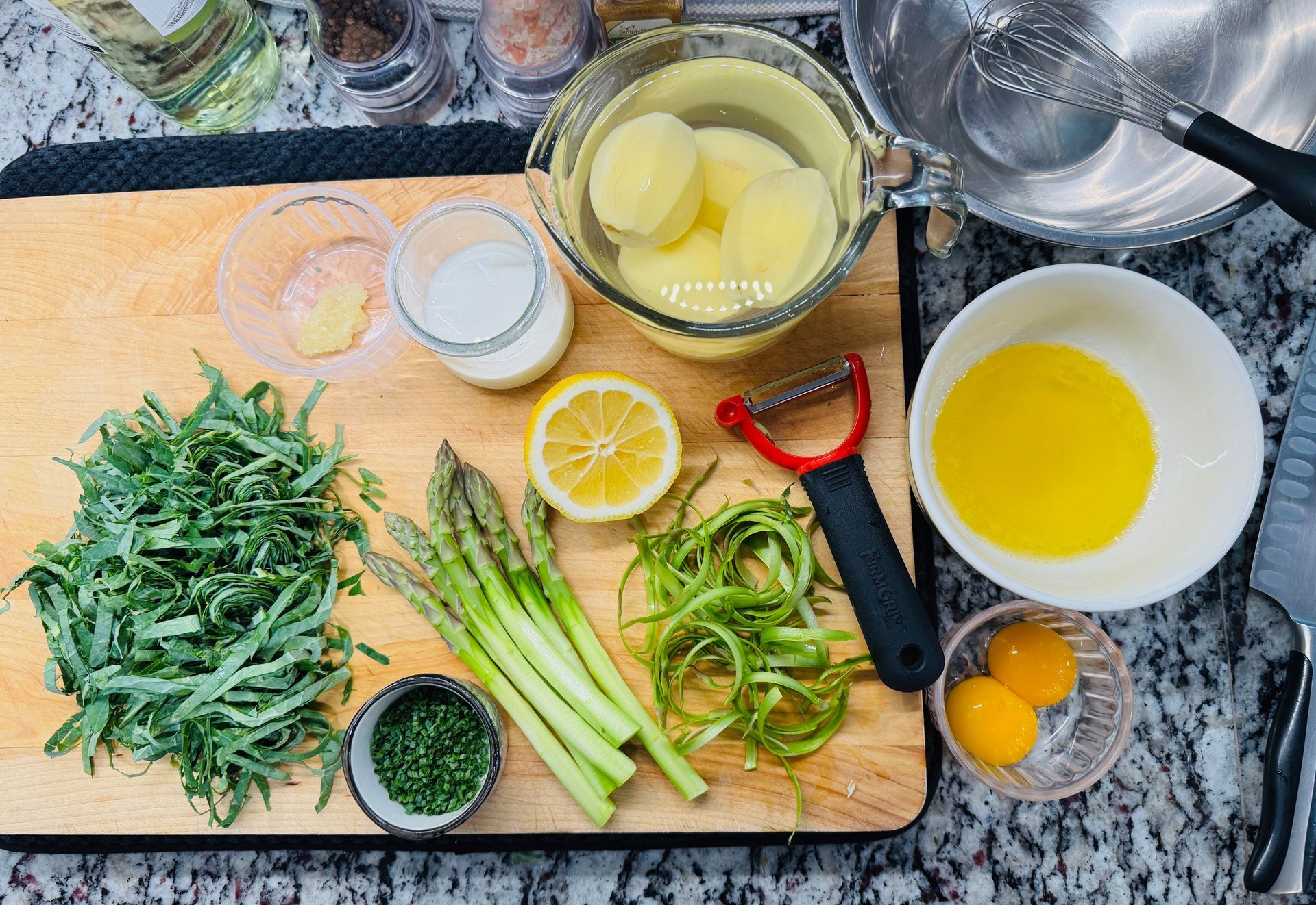 Clarified butter, peeled gold potatoes, peeled asparagus and chiffonade kale ready to cook.