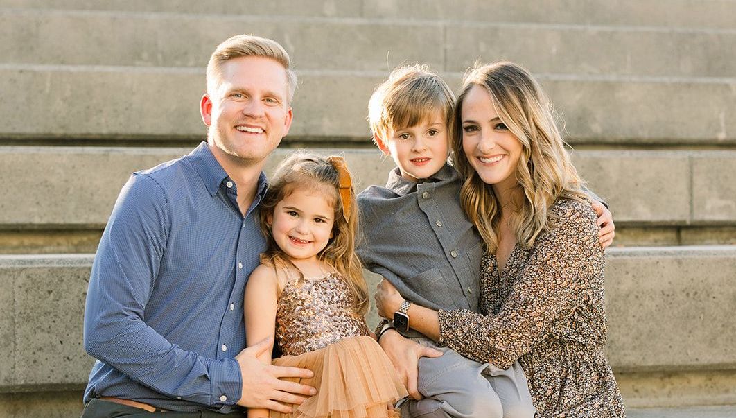 A family is sitting on a set of stairs posing for a picture.