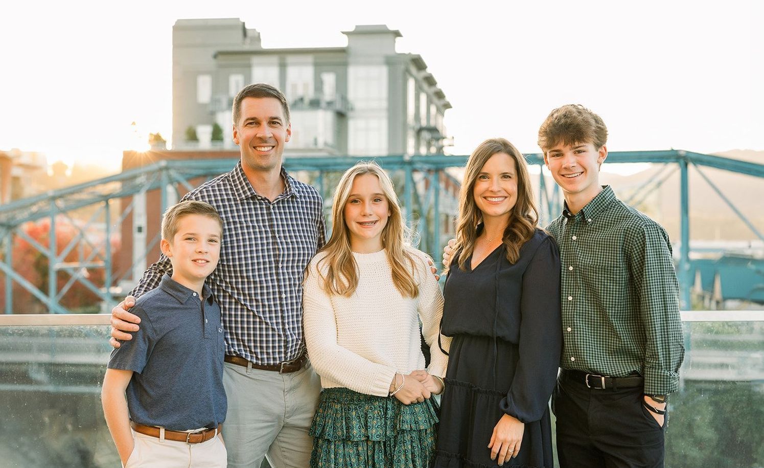 A family is posing for a picture in front of a bridge.