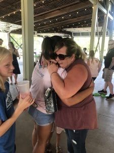 A group of people are hugging each other in a pavilion.