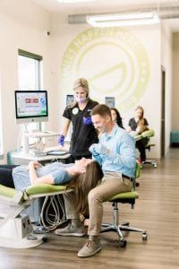 A man and a woman are sitting in a dental chair in a dental office.