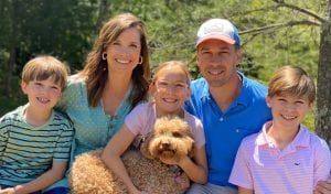 A family is posing for a picture with a dog.