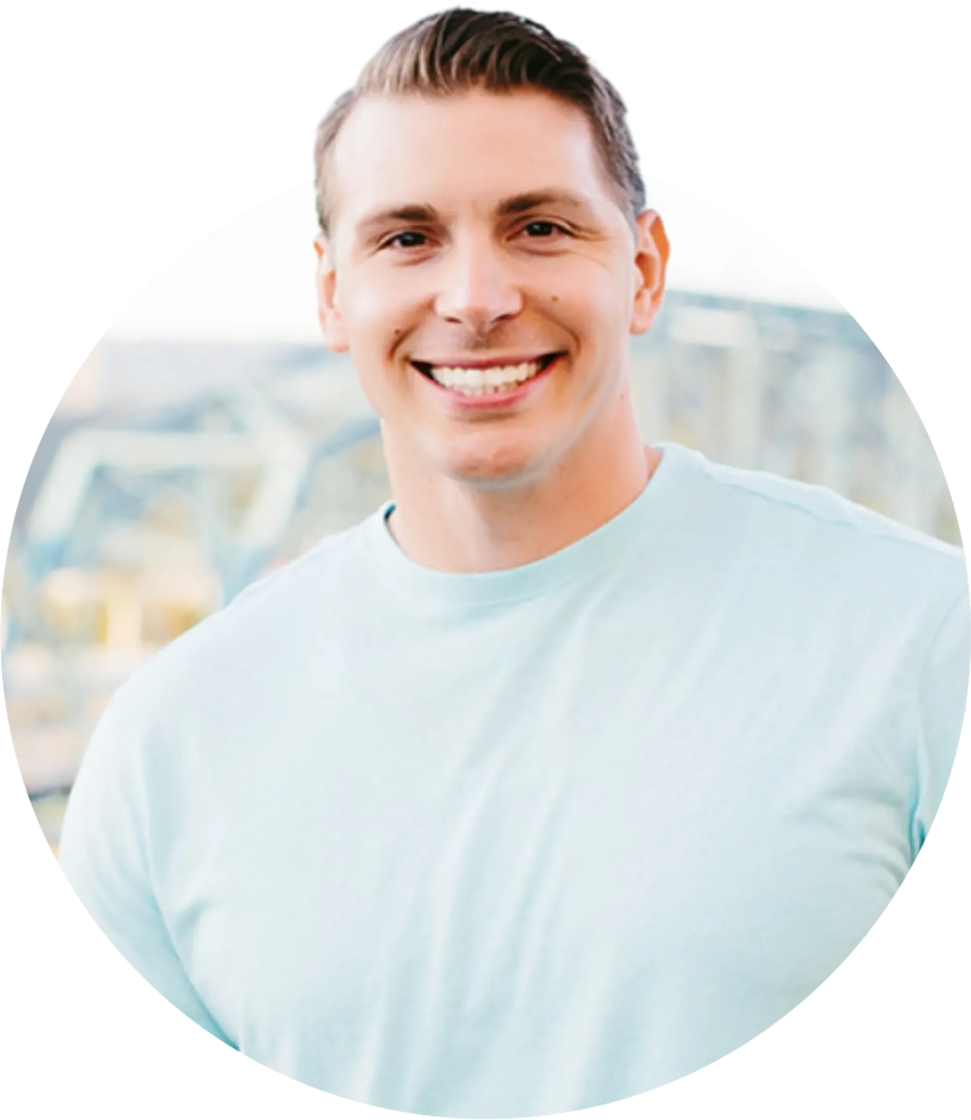 A man in a light blue shirt is smiling for the camera.