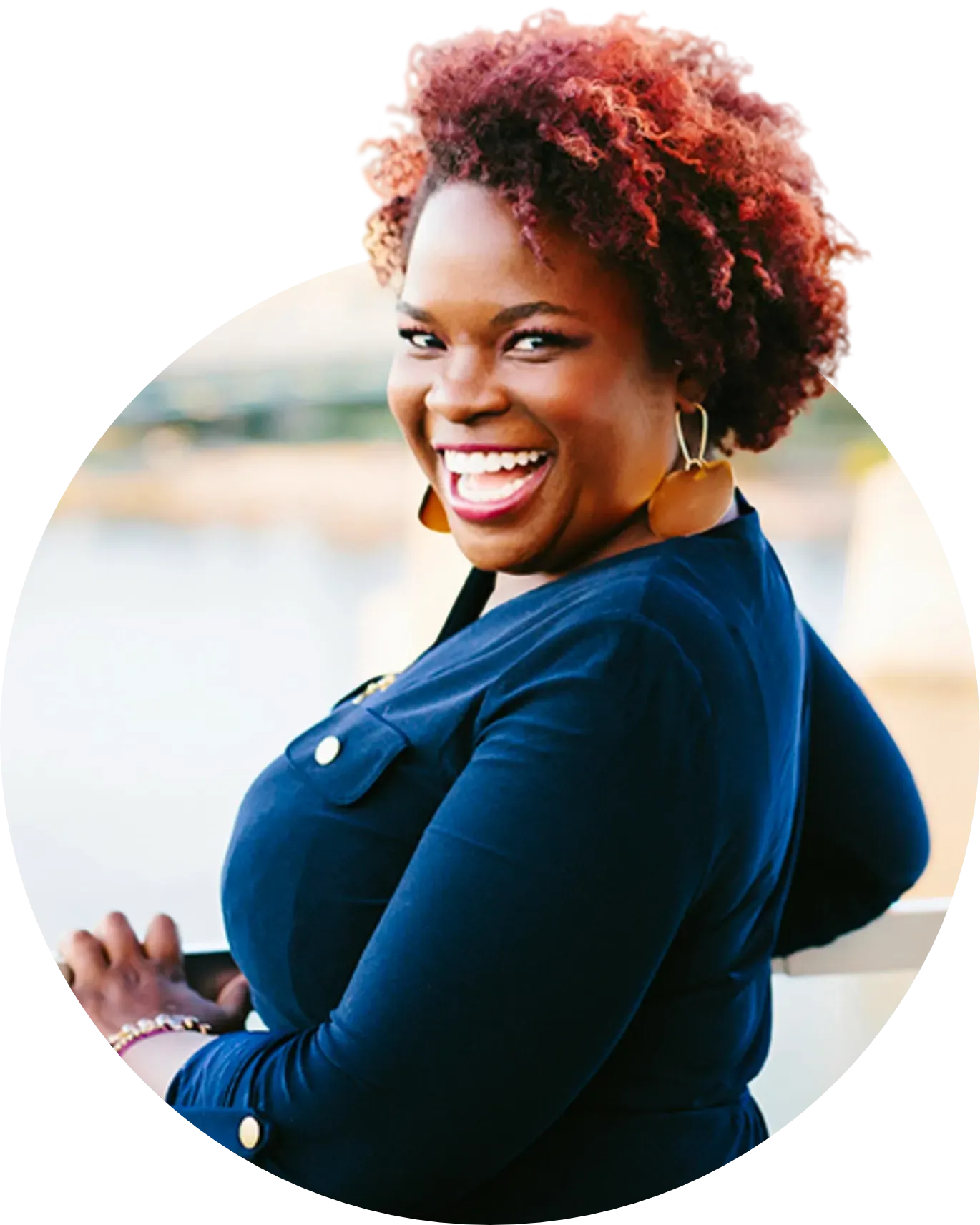 A woman with red hair is smiling and wearing a blue shirt
