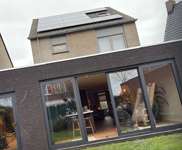 Gebouw met zonnepanelen, aanbouw met glazen deuren, 
