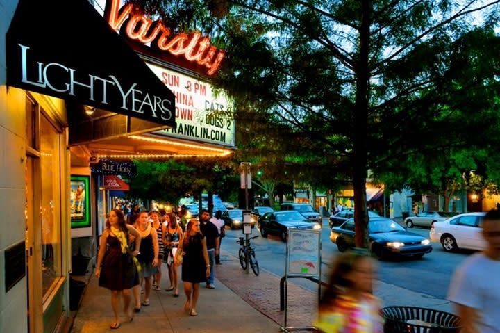 A group of people are walking in front of a varsity theater