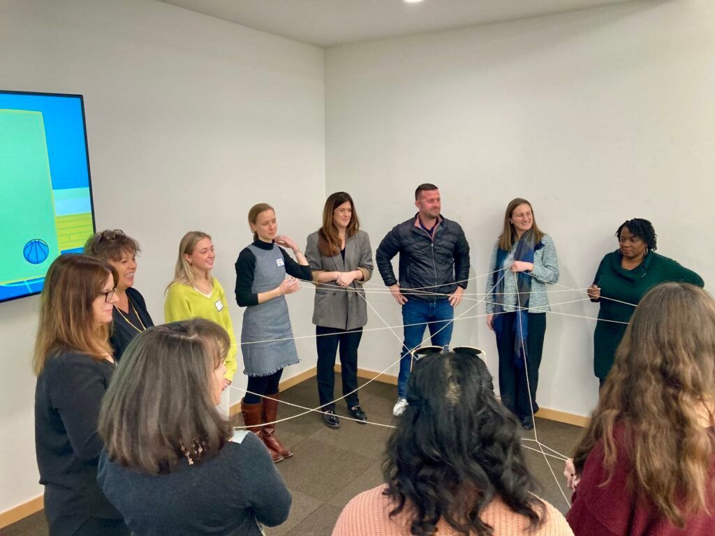 A group of people are standing in a room holding a string.