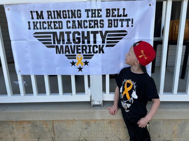 A child stands by a white sign that reads: