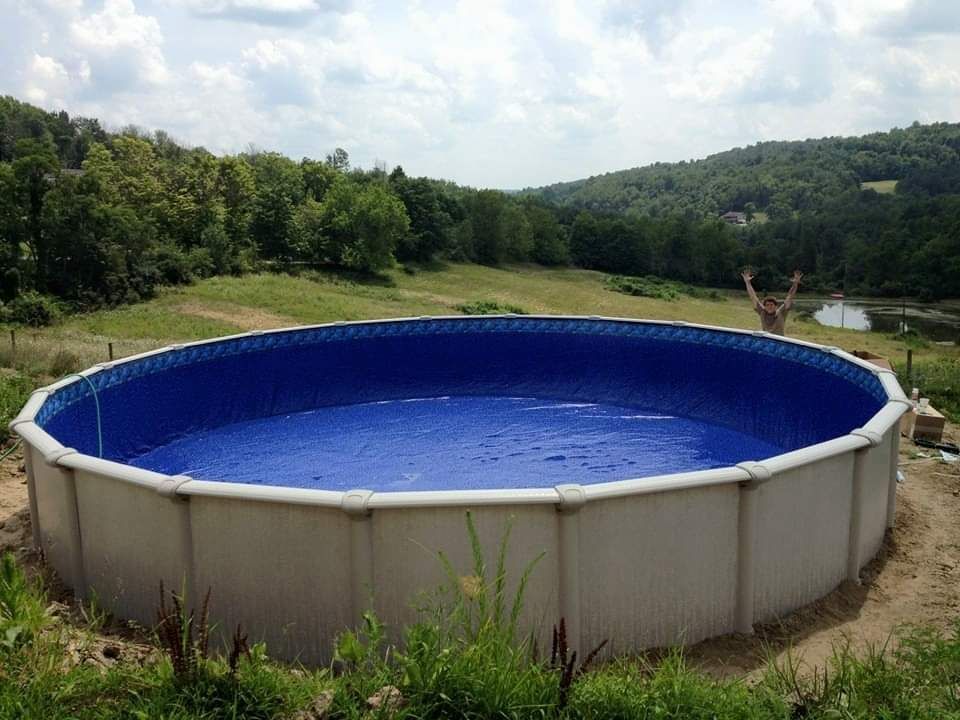 A large swimming pool is sitting in the middle of a field.