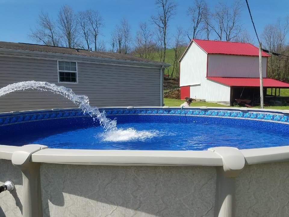 A swimming pool with a fountain in it and a barn in the background