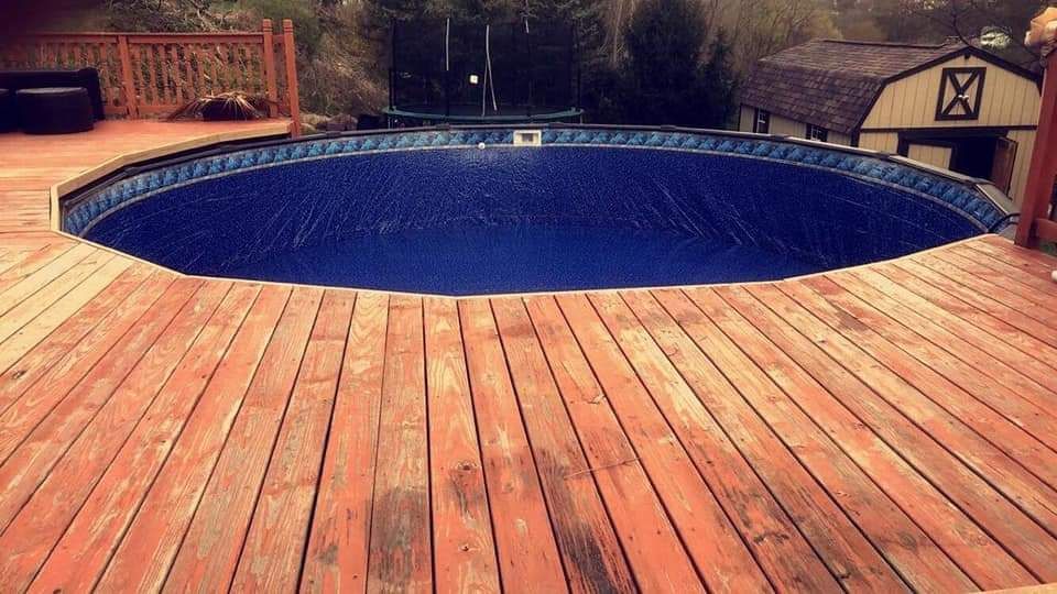 A swimming pool is sitting on top of a wooden deck.