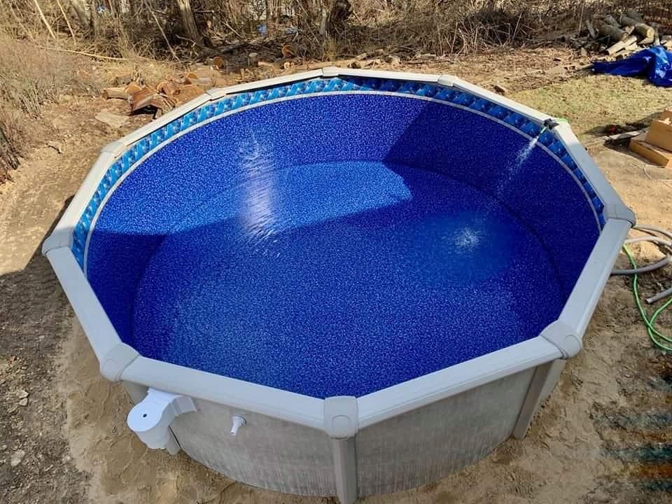 A swimming pool with a blue liner is sitting in the dirt.