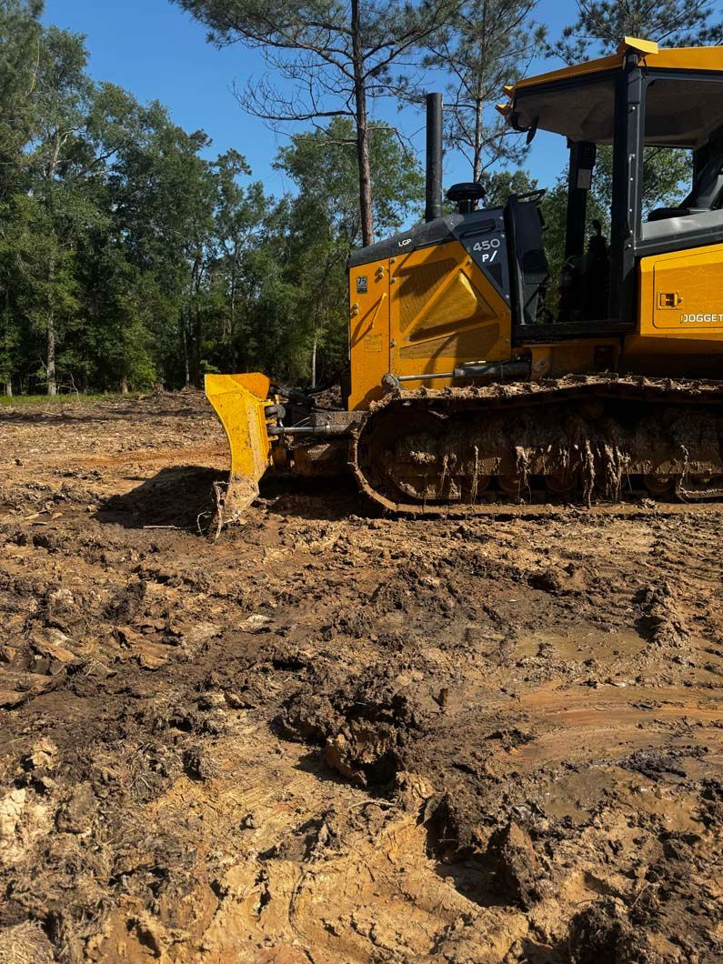 A yellow bulldozer is driving through a muddy field.