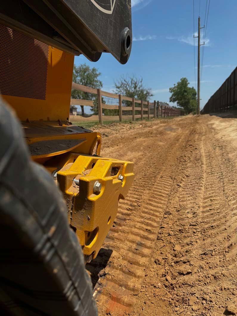 A yellow bulldozer is driving down a dirt road.