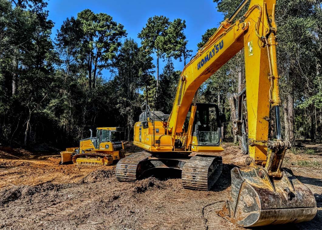 A yellow excavator is sitting in the middle of a dirt field.