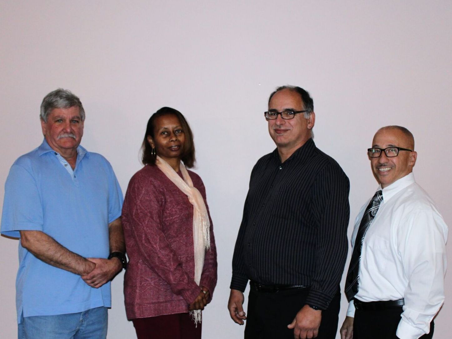 A group of people standing next to each other in front of a wall