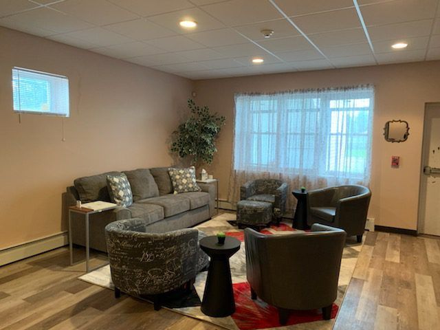 A living room with a couch , chairs , tables and a window.